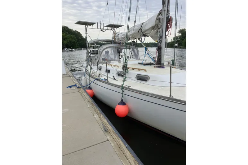 Slide: The Image of 1982 Tartan 33 sailboat docked with red fenders, calm water background. - 2