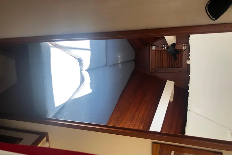 Slide: The Image of Interior cabin of a 1982 Tartan 33 sailboat with wooden paneling and blue cushions. - 21