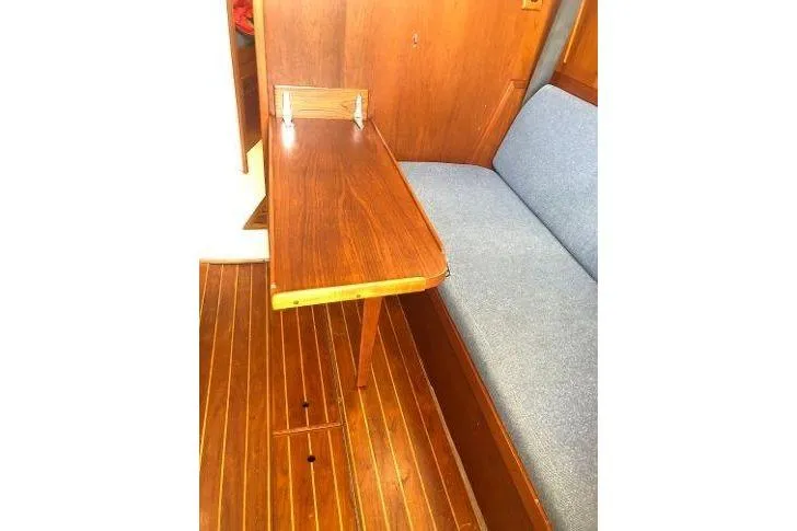 Slide: The Image of 1982 Tartan 33 interior with wooden table and blue cushioned seating. - 22