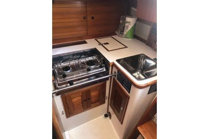 Slide: The Image of 1982 Tartan 33 yacht kitchen with stove, sink, and wooden cabinetry. - 28