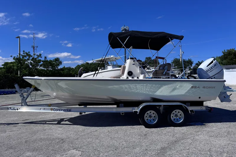 The Image of 2026 Sea Born FX22 Bay boat on trailer with Suzuki outboard motor, under clear blue sky. - 0