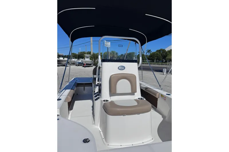 Slide: The Image of 2026 Sea Born FX22 Bay boat interior with seating and canopy, parked outdoors. - 16