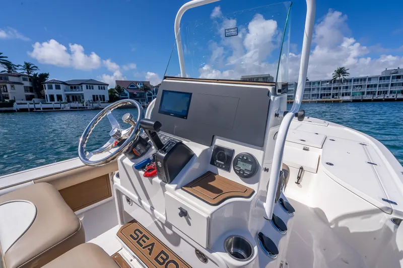 Slide: The Image of 2026 Sea Born FX22 Bay boat dashboard with steering wheel and controls, dockside view. - 27