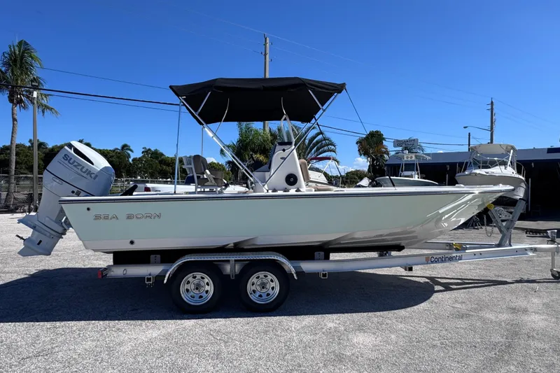 Slide: The Image of 2026 Sea Born FX22 Bay boat on trailer, parked outdoors under clear blue sky. - 5