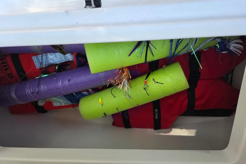 Slide: The Image of Storage compartment with pool noodles, fishing lures, and life jackets on a 2023 Sportsman Open 232 boat. - 32