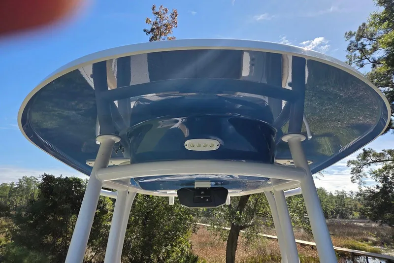 Slide: The Image of 2023 Sportsman Open 232 Center Console T-top with blue underside, set against a clear sky. - 36