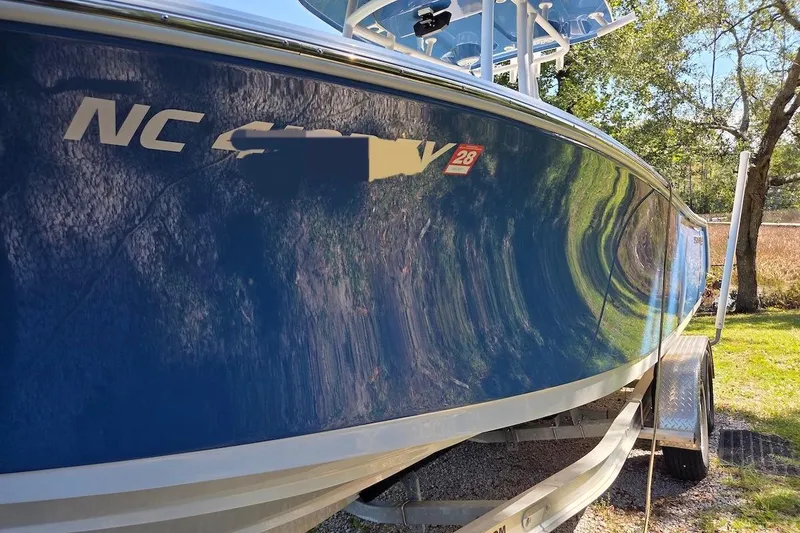 Slide: The Image of 2023 Sportsman Open 232 Center Console boat on trailer, side view with blue hull. - 38