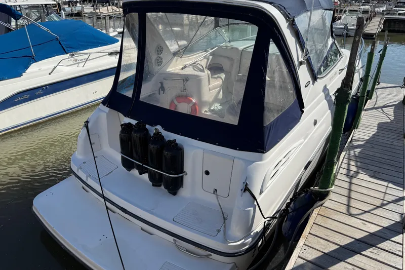 Slide: The Image of 1999 Chaparral Signature 300 boat docked, featuring a covered cockpit and fenders. - 2
