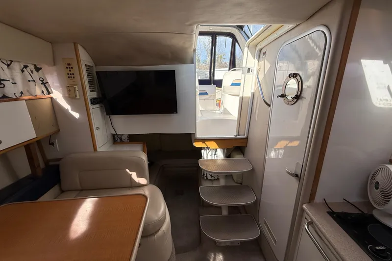 Slide: The Image of 1999 Chaparral Signature 300 cabin interior with seating, table, and steps to deck. - 29