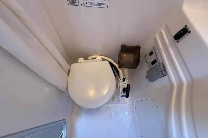 Slide: The Image of 1999 Chaparral Signature 300 boat bathroom with compact toilet and control panel. - 33