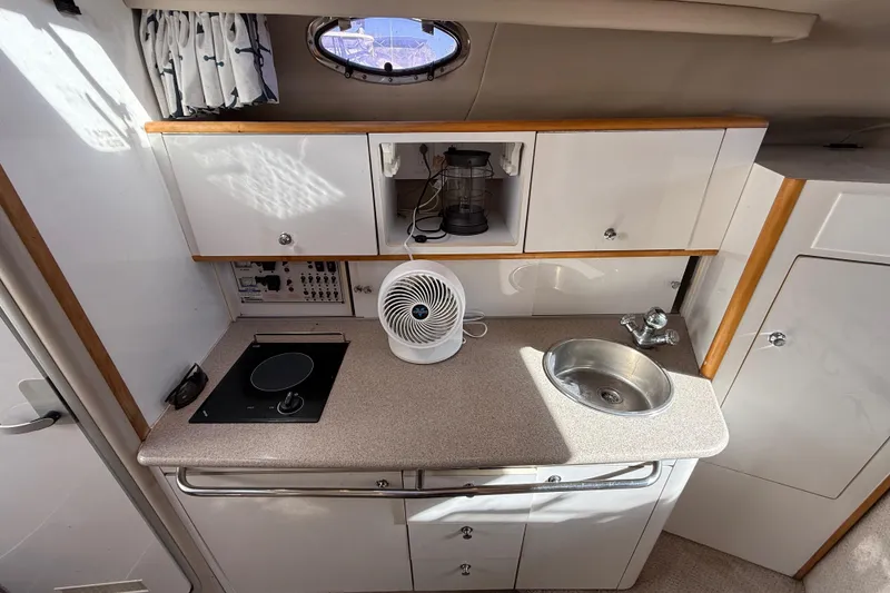 Slide: The Image of 1999 Chaparral Signature 300 boat interior kitchen with stove, sink, and fan. - 34