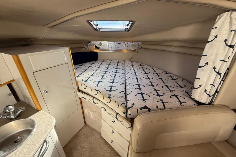 Slide: The Image of 1999 Chaparral Signature 300 cabin interior with anchor-themed bedding and compact kitchenette. - 38