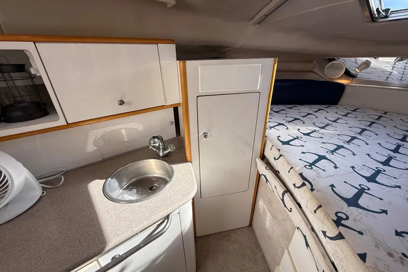 Slide: The Image of 1999 Chaparral Signature 300 cabin interior with sink, storage, and anchor-patterned bedding. - 39