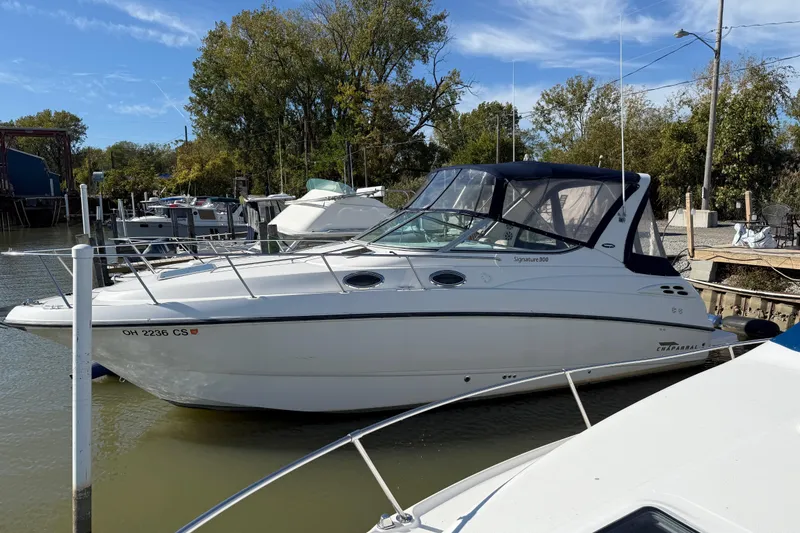 Slide: The Image of 1999 Chaparral Signature 300 boat docked in a marina, surrounded by trees and other boats. - 7