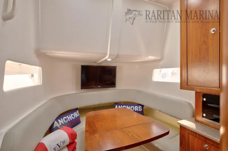 Slide: The Image of 2016 Regulator 41 boat interior with cozy seating, wooden table, and mounted TV. - 12