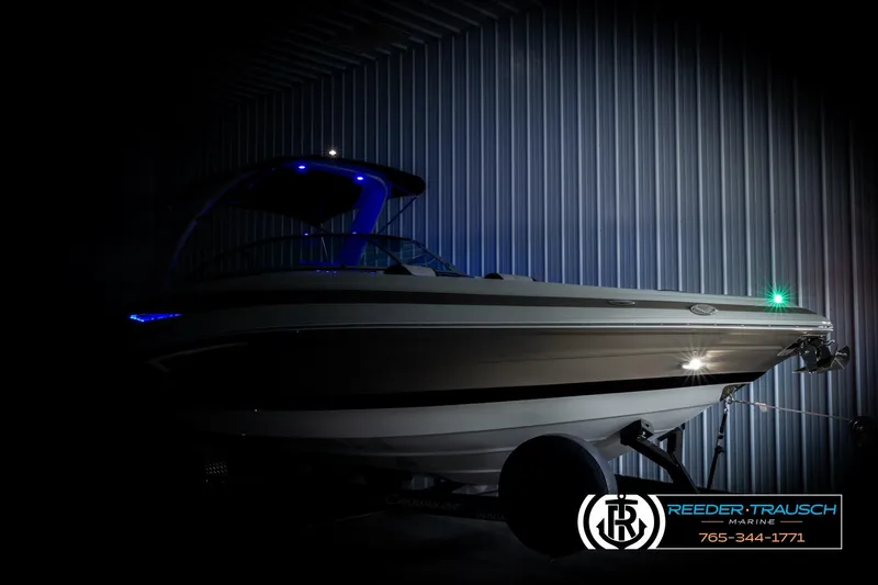 Slide: The Image of 2022 Crownline 265 SS boat with blue LED lights in a dimly lit showroom. - 4