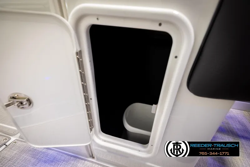 Slide: The Image of Open storage compartment on 2022 Crownline 265 SS boat, featuring sleek design and secure latch. - 64