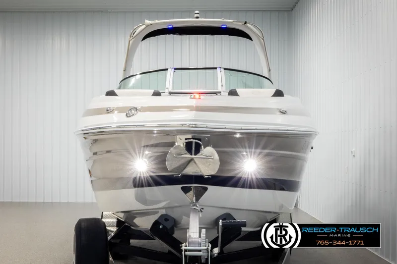 Slide: The Image of 2022 Crownline 265 SS boat in showroom, front view with trailer and lights on. - 8