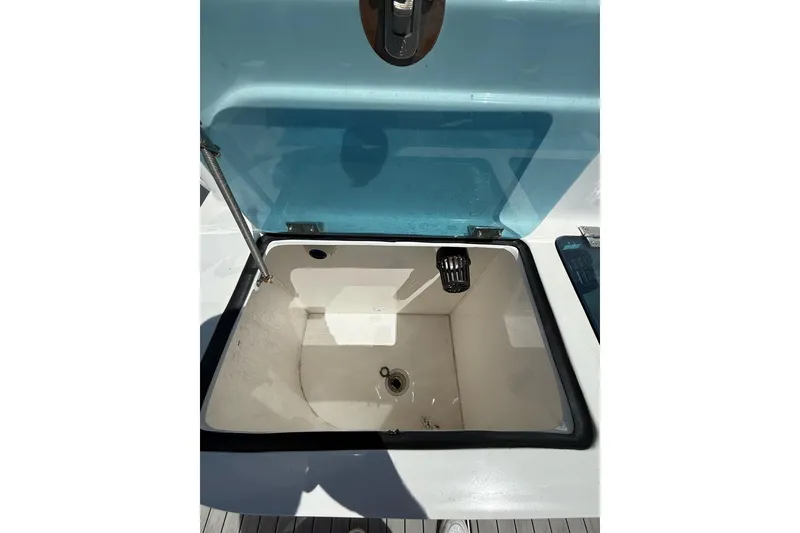 Slide: The Image of Open storage compartment on 2021 Custom Infusion 34 CC boat, featuring a blue lid. - 24