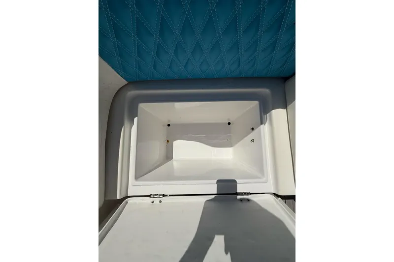 Slide: The Image of Open storage compartment on 2021 Custom Infusion 34 CC boat with blue quilted upholstery. - 27