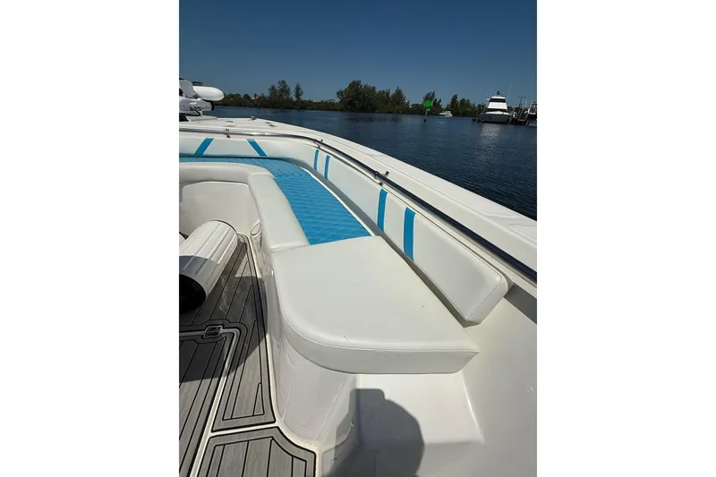 Slide: The Image of Custom Infusion 34 CC 2021 boat with white and blue seating, docked on a sunny day. - 6