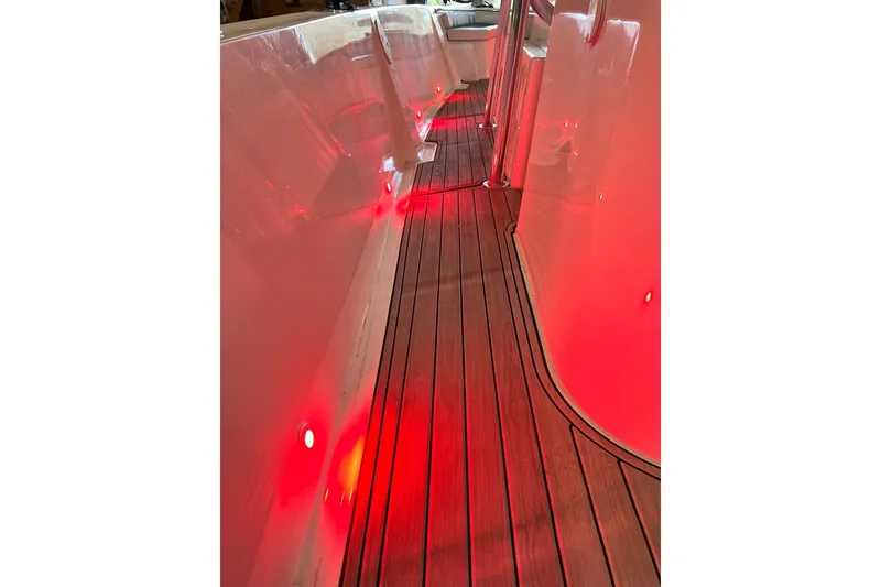 Slide: The Image of Custom Infusion 34 CC 2021 boat interior with red LED lighting and wooden flooring. - 87
