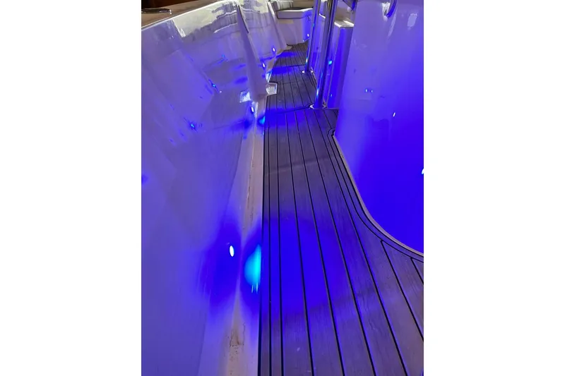 Slide: The Image of Custom Infusion 34 CC 2021 boat interior with blue LED lighting and sleek wooden flooring. - 88