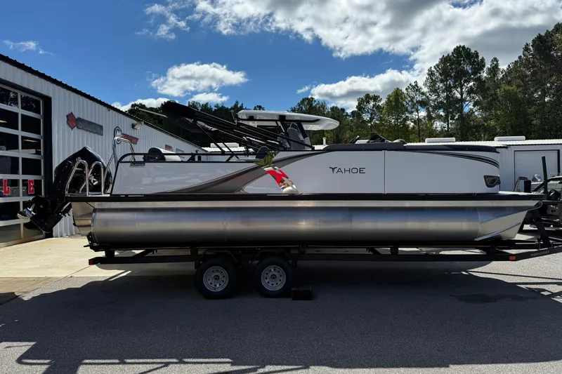 Slide: The Image of 2026 Tahoe Pontoon LTZ Versatile Rear Lounger on trailer, parked outside dealership. - 8