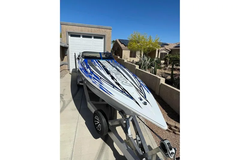 Slide: The Image of 2001 Fountain 35 Lightning speedboat on trailer, vibrant blue and white design, parked in driveway. - 11