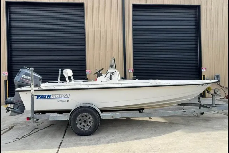 Slide: The Image of 2000 Pathfinder 1806 V boat on trailer with Yamaha motor, parked outside warehouse. - 3