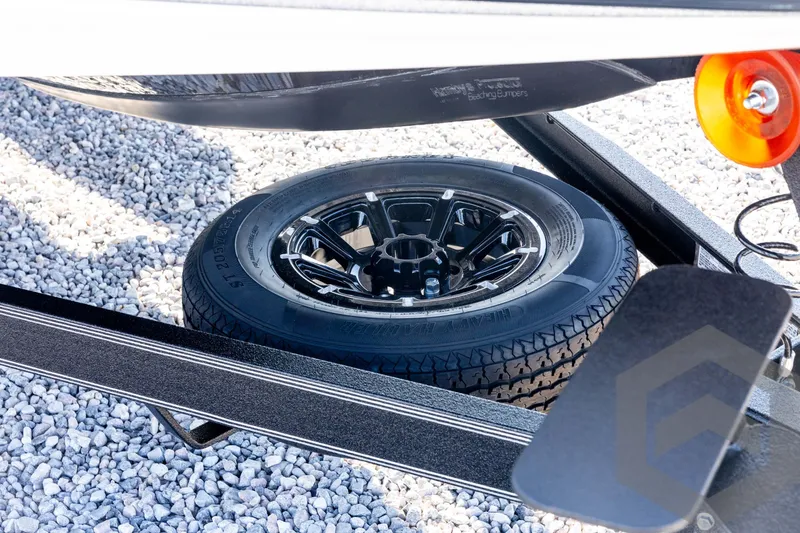 Slide: The Image of Spare tire on a 2026 Skeeter ZXE20 trailer, resting on gravel. - 11
