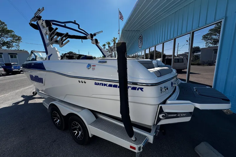 Slide: The Image of 2022 Malibu Wakesetter 23 LSV boat on trailer outside a blue building. - 2
