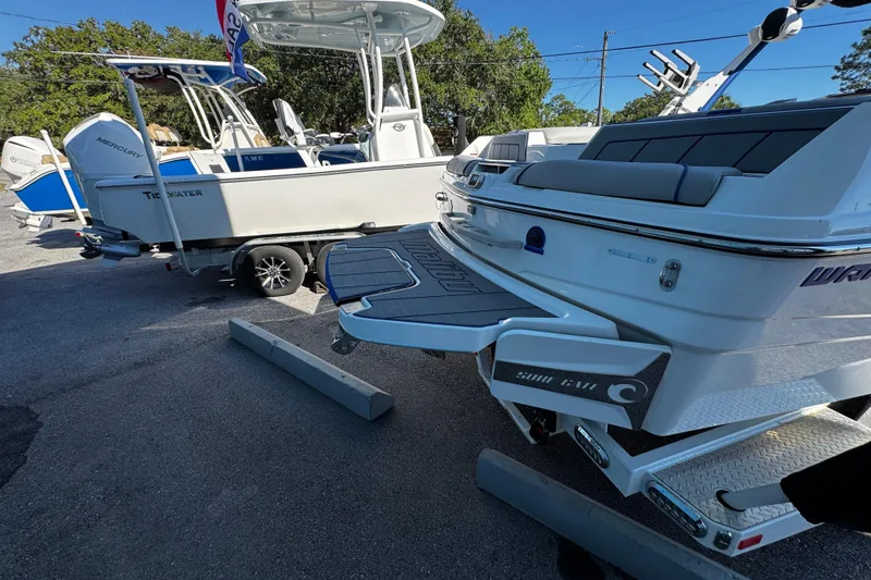 Slide: The Image of 2022 Malibu Wakesetter 23 LSV boat with swim platform, parked beside another boat. - 27