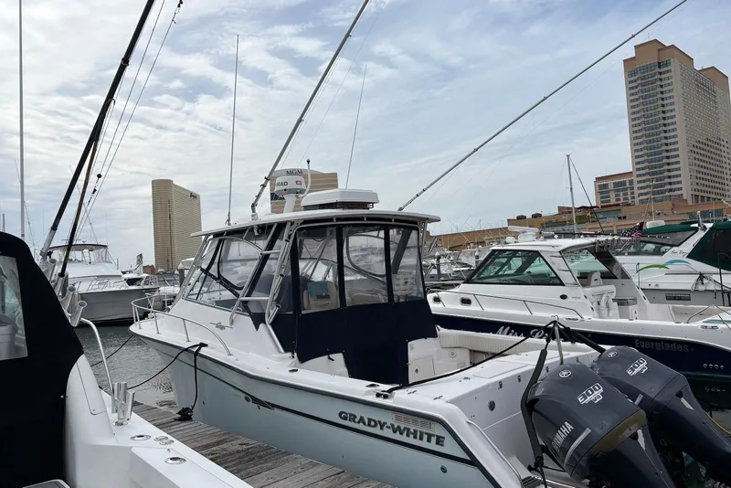 Slide: The Image of 2004 Grady-White Express 330 boat docked in marina with cityscape background. - 1