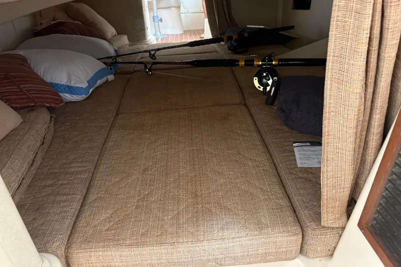 Slide: The Image of 2004 Grady-White Express 330 cabin interior with fishing rods and cushions. - 10