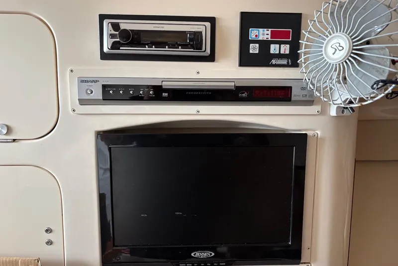 Slide: The Image of 2004 Grady-White Express 330 cabin electronics with fan, stereo, and TV setup. - 12