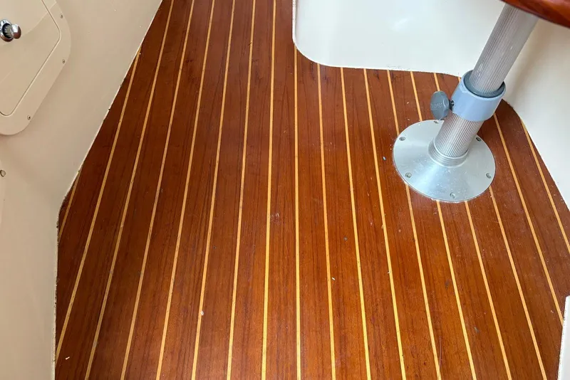 Slide: The Image of Teak flooring on 2004 Grady-White Express 330 boat interior with metal table base. - 15