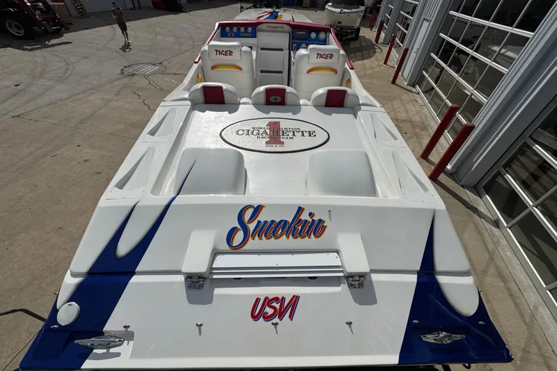 Slide: The Image of 2004 Cigarette 42 Tiger boat with "Smokin" and "USVI" decals, docked near a garage. - 6