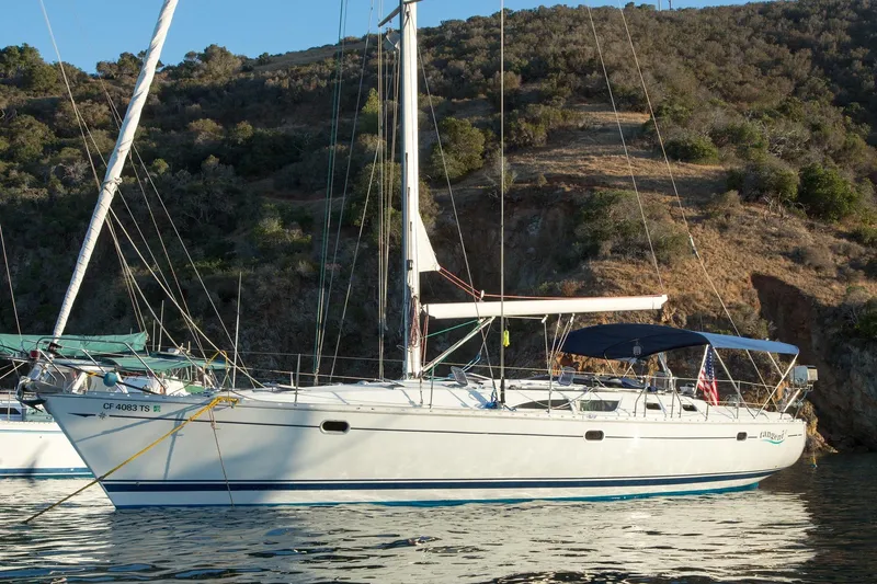 Slide: The Image of 2002 Jeanneau Sun Odyssey 45.2 sailboat anchored near a rocky shoreline. - 1