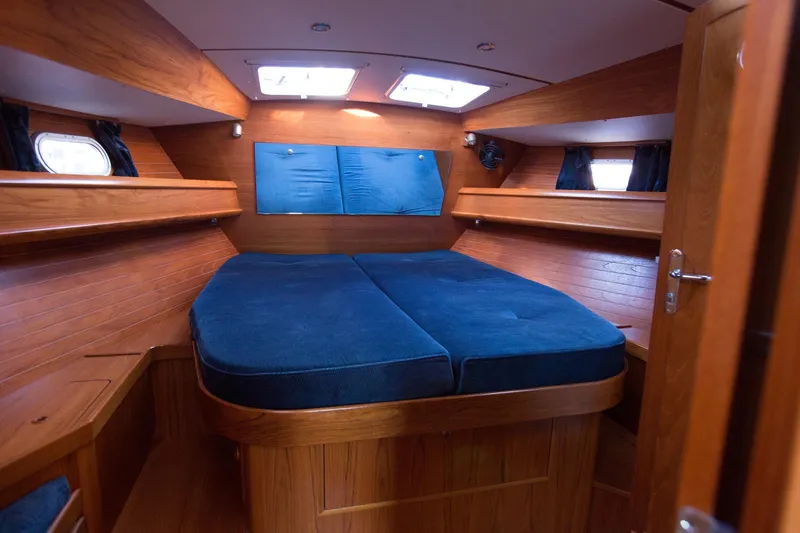 Slide: The Image of Cozy cabin interior of 2002 Jeanneau Sun Odyssey 45.2 with blue cushions and wooden finish. - 13