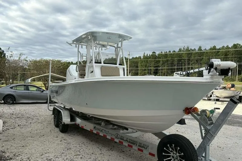 Slide: The Image of 2026 Blazer Bay 2700 Hybrid boat on trailer, parked outdoors under cloudy sky. - 17