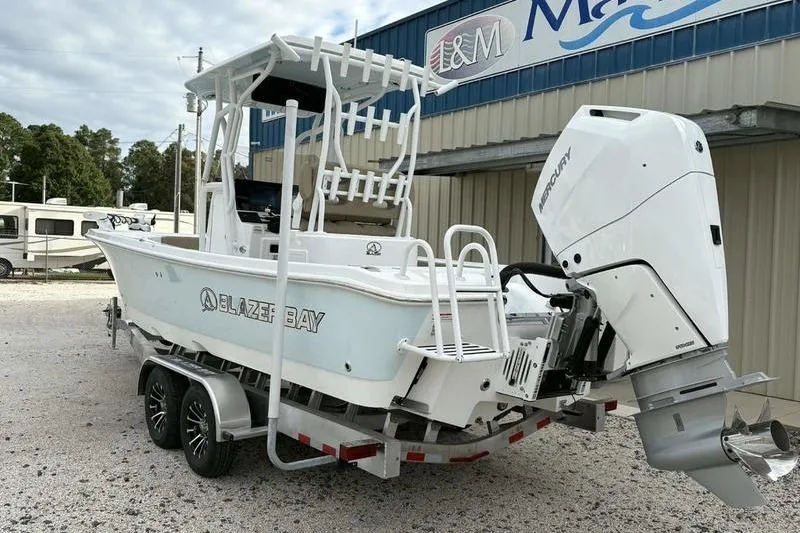 Slide: The Image of 2026 Blazer Bay 2700 Hybrid boat with Mercury engine on trailer, parked outside dealership. - 22