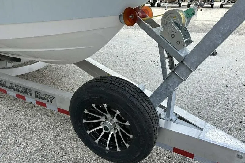 Slide: The Image of Trailer with Blazer Bay 2700 Hybrid boat, 2026 model, on a gravel surface. - 3