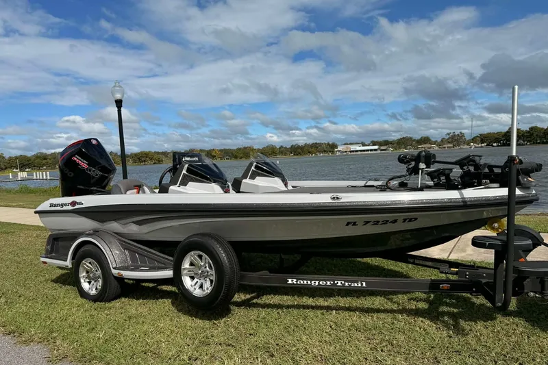The Image of 2022 Ranger Z518 boat on trailer by a lake under a blue sky. - 0