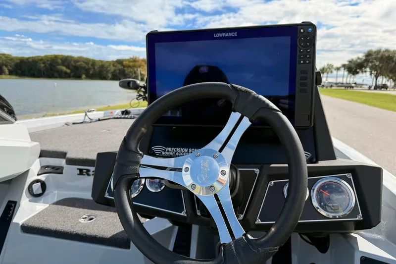 Slide: The Image of 2022 Ranger Z518 boat dashboard with steering wheel and Lowrance display by a lake. - 7