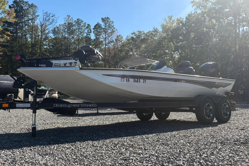 Slide: The Image of 2022 Boomeranger 198P boat on trailer, parked outdoors with trees in background. - 1