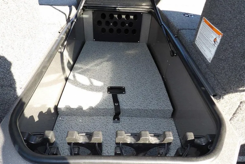 Slide: The Image of 2026 Lund 2075 Impact XS boat storage compartment with rod holders and carpeted interior. - 41