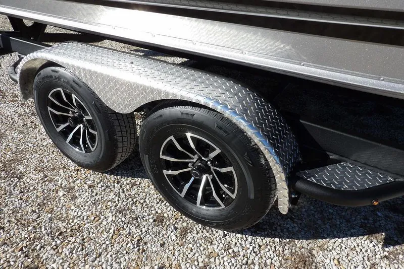 Slide: The Image of 2026 Lund 2075 Impact XS trailer with dual black alloy wheels on gravel. - 49