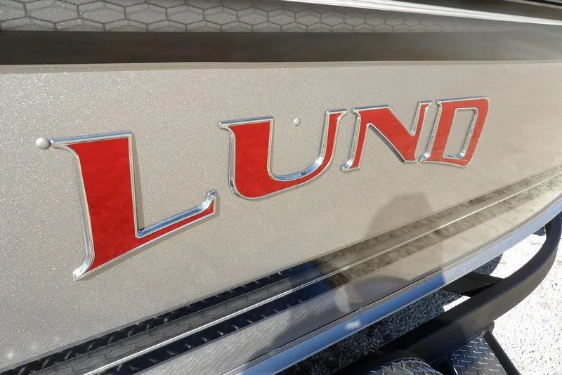 Slide: The Image of 2026 Lund 2075 Impact XS boat logo with red lettering on metallic surface. - 51