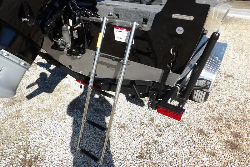 Slide: The Image of 2026 Lund 2075 Impact XS boat with ladder and motor, parked on gravel. - 59